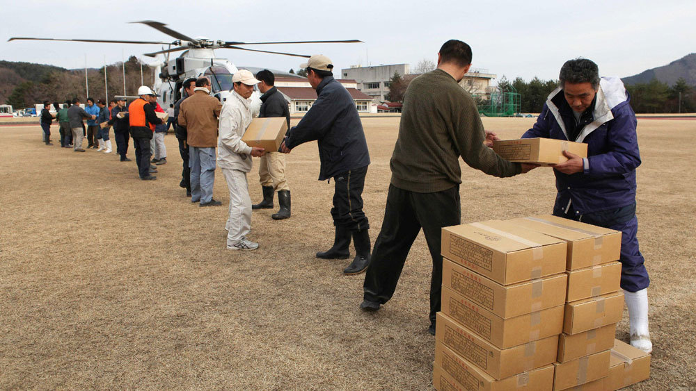 Local residents and town staff carry out relief supplies from a helicopter in the town of Onagawa in Miyagi prefecture on Monday, three days after a massive 8.9 magnitude earthquake and tsunami devastated the coast of eastern Japan.